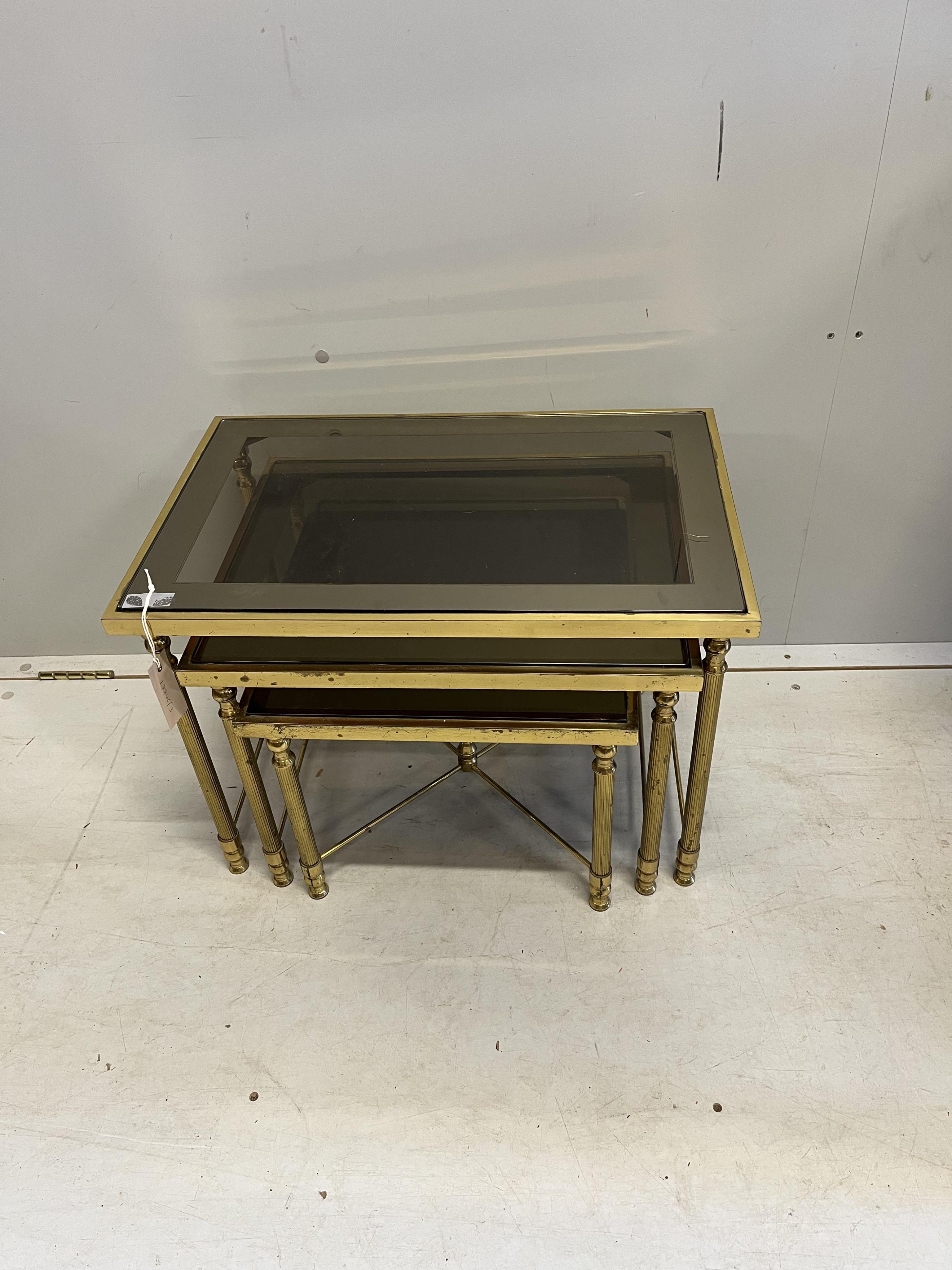 A Maison Jenson style nest of three brass smoked glass tables, width 57cm, depth 37cm, height 40cm